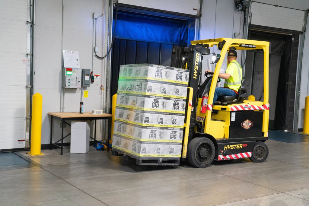 Man driving yellow battery-powered fork lift indoors